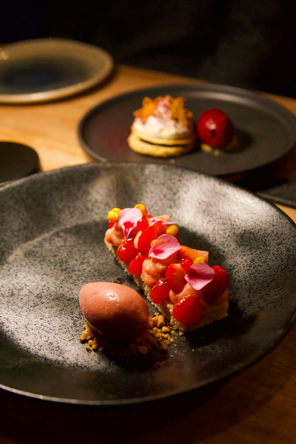 Gourmet desserts on dark plates in a fine dining setting.