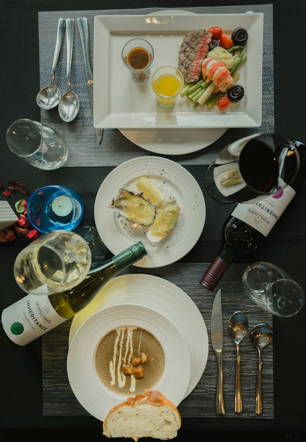 Elegant multi-course meal with steak, lobster, oysters, and wine.
