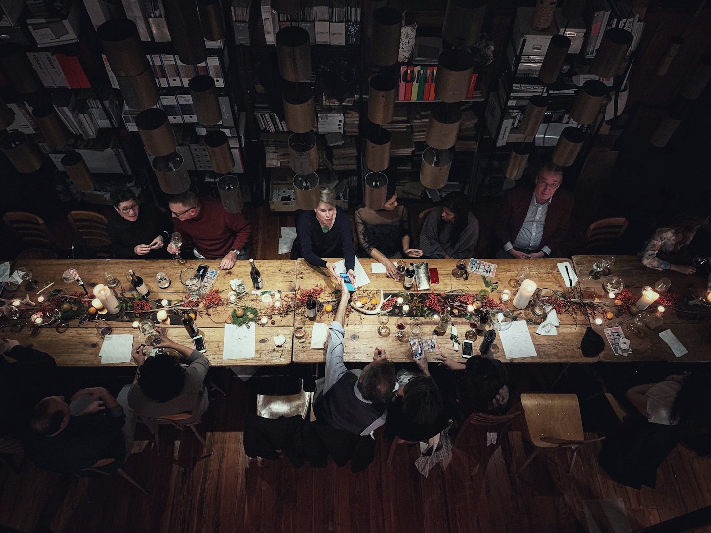 People gather for a social dinner at a rustic wooden table.